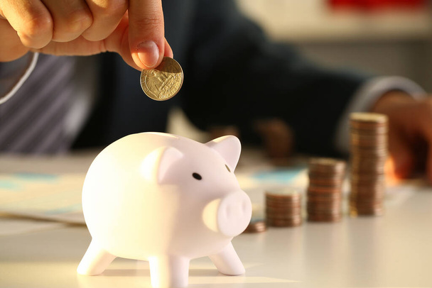 Businessman hand throws a coin into piggy bank - Photo, Image