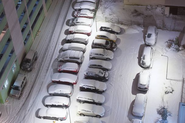 Many parking cars in snow on night winter parking lots. aerial view on parking - Foto, Imagen
