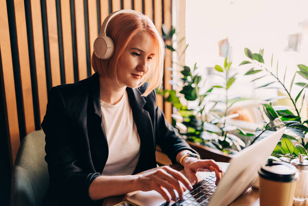 Lady freelancer wearing headset, communicating with client via video computer call. Millennial professional female - Photo, Image