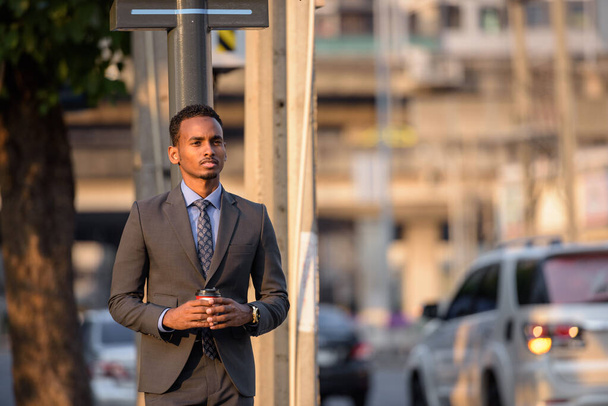 Schöner junger afrikanischer Geschäftsmann im Anzug in der Stadt - Foto, Bild