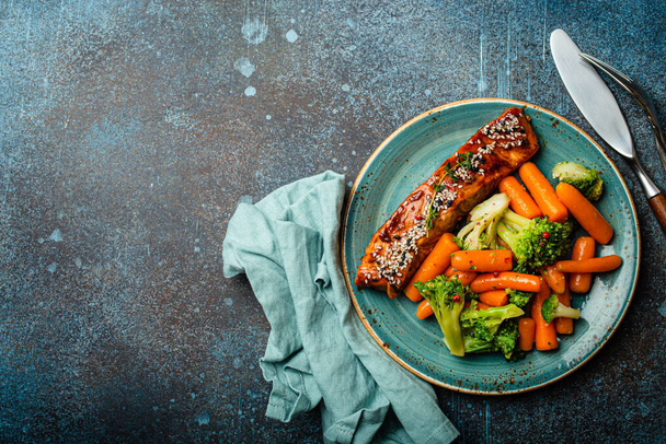 Grilled salmon fillet steak in teriyaki sauce with roasted vegetables carrot and broccoli - Фото, изображение