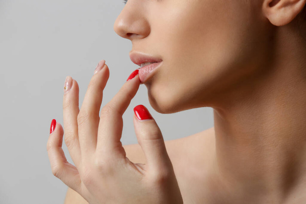 Beauty portrait of gorgeous young woman touching lips, close up, studio shot - Фото, изображение