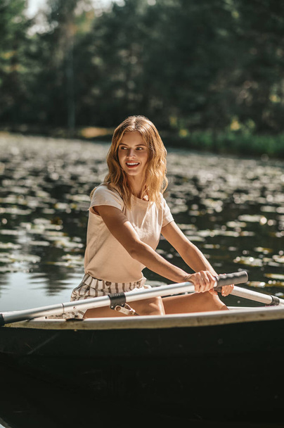 A woman sitting in a boat and oaring - Foto, afbeelding