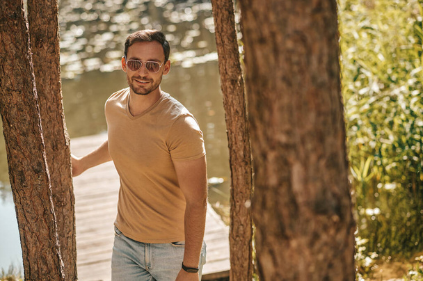 A young man in sunglasses in the forest near the river - Foto, Bild