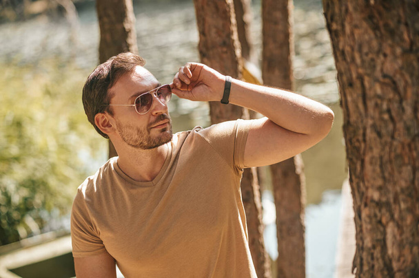 A young man in sunglasses in the forest near the river - Foto, imagen