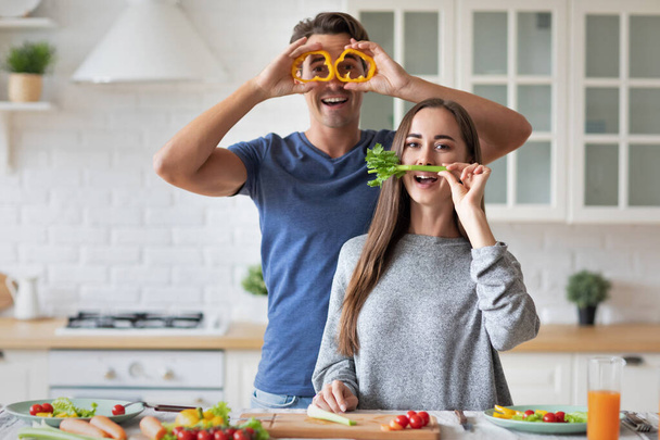 Happy young couple have fun in modern kitchen indoor while preparing vegetables food for lunch. - Foto, immagini