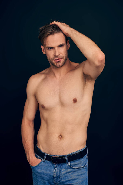 Handsome young bearded man isolated. Topless muscular man in jeans posing on dark blue background. Serious man looking at camera. - Фото, зображення