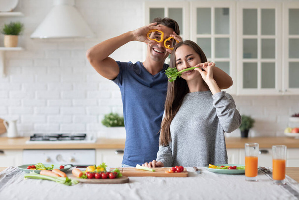 Handsome man and attractive young woman having fun making salad together. Healthy lifestyle concept. - Fotoğraf, Görsel