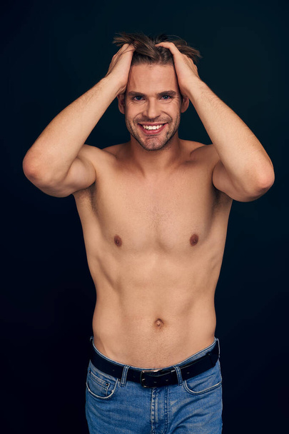 Handsome young bearded man isolated. Topless muscular man in jeans posing on dark blue background. Serious man looking at camera. - Foto, Imagen
