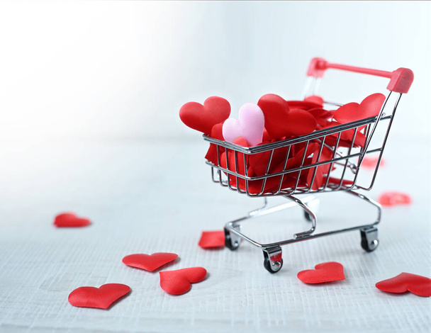 Shopping trolley with pink hearts isolated on grey background. Shopping concept. - Foto, Imagem