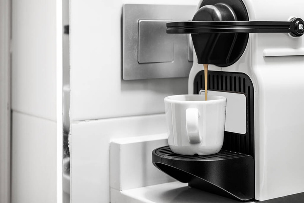 Freshly brewed coffee dripping into a white porcelain cup - Foto, afbeelding
