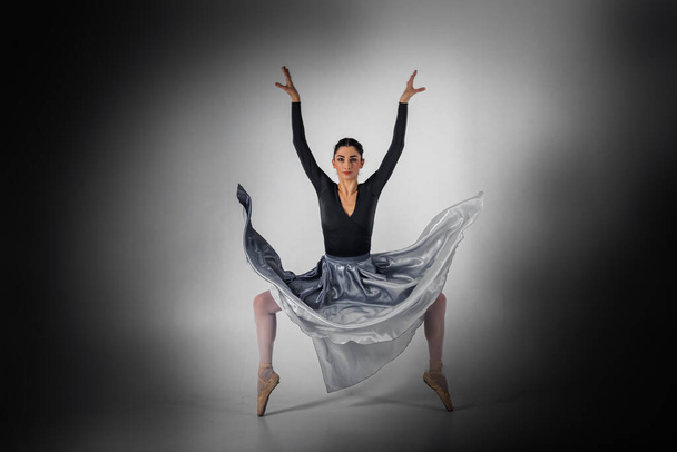 バレリーナ。プロの服装、靴、青い無重力のスカートを身に着けている若いエレガントなバレエダンサーは、彼女のダンススキルを示しています。古典バレエの美しさ - 写真・画像