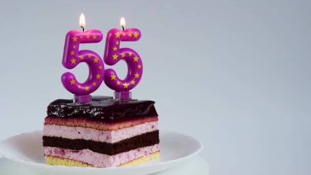 Appetizing birthday cake with burning candles for 55th anniversary on a white rotating plate - Video, Çekim