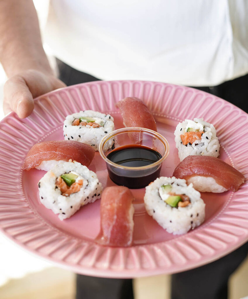 A man with a tray with assorted pieces of sushi. California roll. - Photo, Image