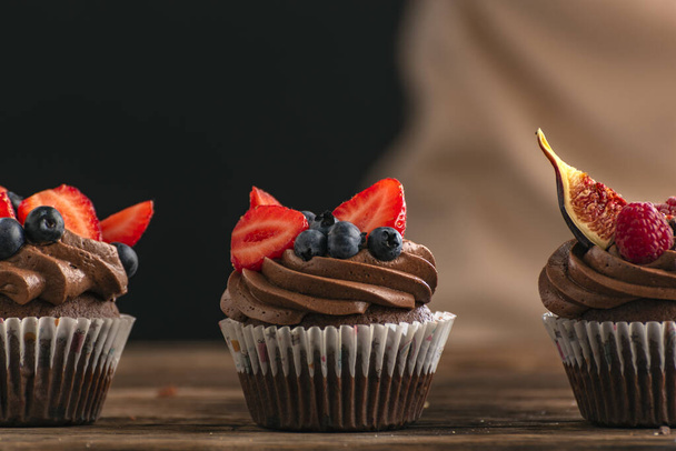 Cupcake con fragole, lamponi, mirtilli, fichi. Muffin al cioccolato decorati con frutta e bacche di stagione - Foto, immagini