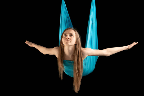 Woman flies on yoga hammock. Portrait of young woman during gymnastic training. Practicing fly yoga - Photo, image