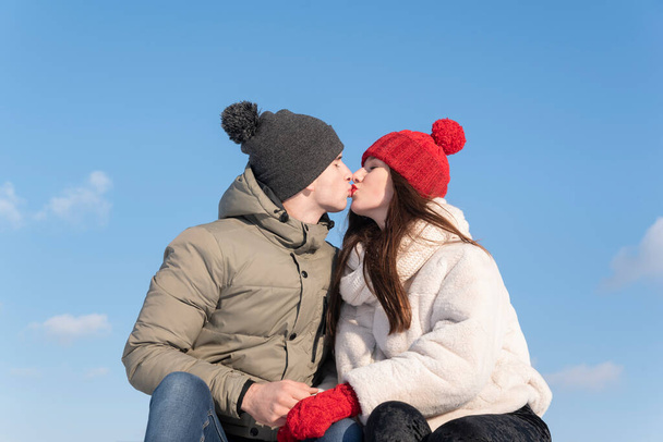 青い空にキスする冬の帽子のカップルを愛する。冬の日付. - 写真・画像