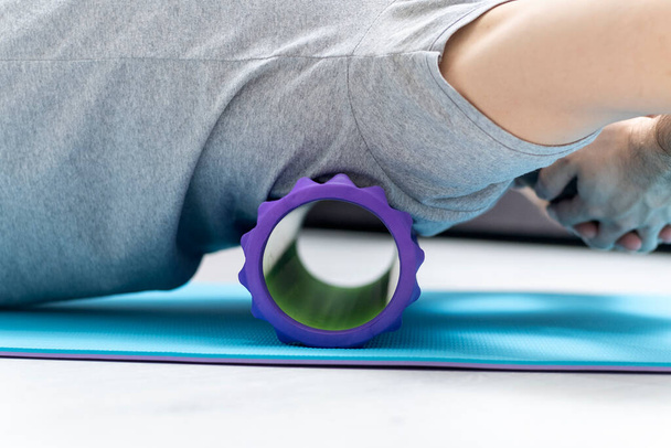 Man uses foam roller massager for relaxation and back pain. Man doing fascia exercise on the floor. Myofascial roller - Fotó, kép