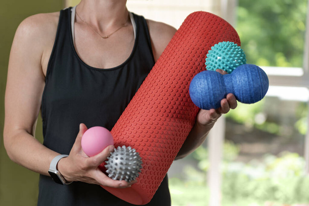 Young athletic woman holds equipment for MFR. Myofascial massage trainer. Different types myofascial rolls - Fotoğraf, Görsel
