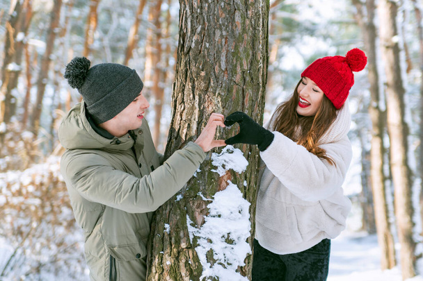 Couple in love in winter forest keeps hands in heart shape sign. - Foto, imagen