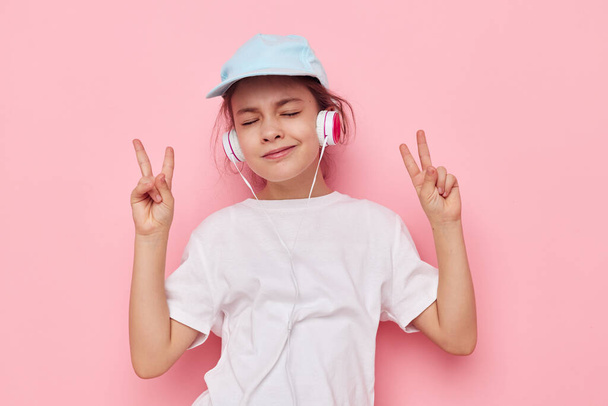 Portrait of happy smiling child girl listening to music on headphones isolated background - Фото, зображення