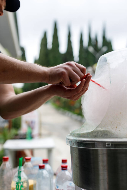 A man cooks cotton candy in the car. Outdoors. Hands close-up, vertical frame - Foto, Imagen