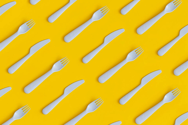 Πλαστικά μαχαιροπίρουνα τροφίμων σε κίτρινο φόντο. Έννοια της ανακύκλωσης πλαστικών και οικολογίας. - Φωτογραφία, εικόνα