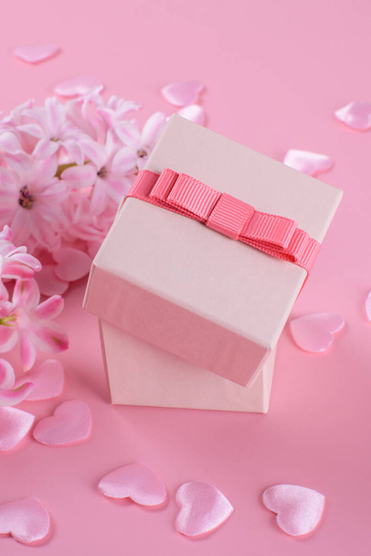 Gift or present box, beautiful pink hyacinth flowers and pink hearts on pink table top view. Flat lay composition for Valentines day, birthday, mother day or wedding, monochrome, selective focus - Foto, afbeelding