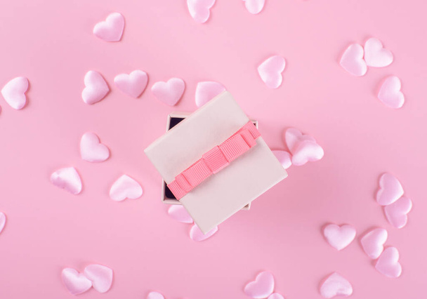Caja regalo o regalo, corazones rosados en la vista superior de la mesa de color rosa. Composición laica plana para el día de San Valentín, cumpleaños, día de madre o boda, monocromo, enfoque selectivo - Foto, Imagen