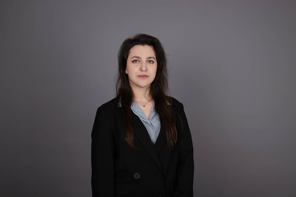attractive confident brunette business woman in blue blouse and black jacket on grey background - Φωτογραφία, εικόνα