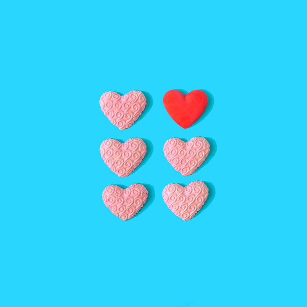 Five pastel pink hearts and one red neatly aligned on bright blue background. Creative concept for Valentine's celebration card or wedding invitation. Flat lay. Minimal spring or summer design. - Fotografie, Obrázek
