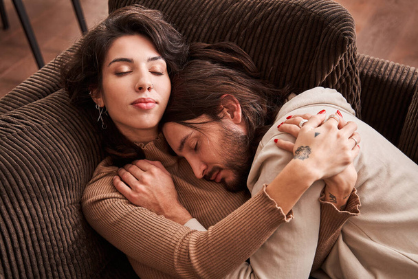 Couple smiling and hugging while laying on sofa at home - Foto, immagini