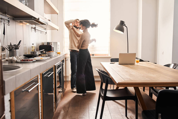 Spouses enjoying tender moment in kitchen at home together - Foto, afbeelding