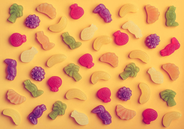 Jelly candies in shape of fruits, trees and birds as pattern on yellow background - Φωτογραφία, εικόνα