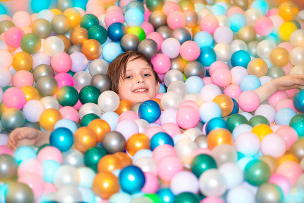 the boy lies in the pool with plastic balls in the play center for children - Photo, image