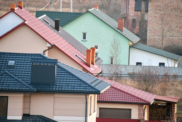 Житлові будинки з верхівками даху покриті металевою та керамічною черепицею в сільській місцевості
 - Фото, зображення
