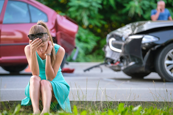 Stressaantunut naiskuljettaja istui kadulla järkyttyneenä auto-onnettomuuden jälkeen. Liikenneturvallisuuden ja vakuutusten käsite - Valokuva, kuva