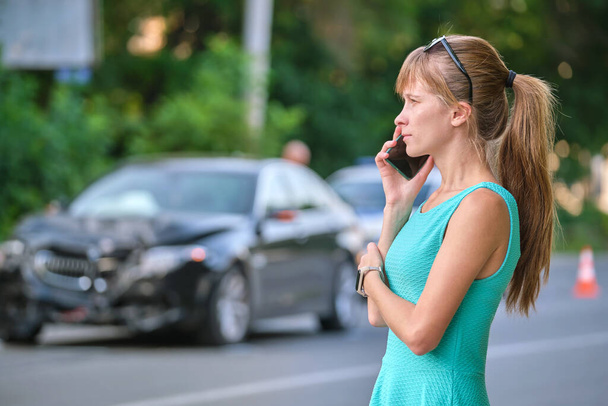 Stressed woman driver talking on mobile phone on street side calling for emergency service after car accident. Road safety and insurance concept - Фото, зображення