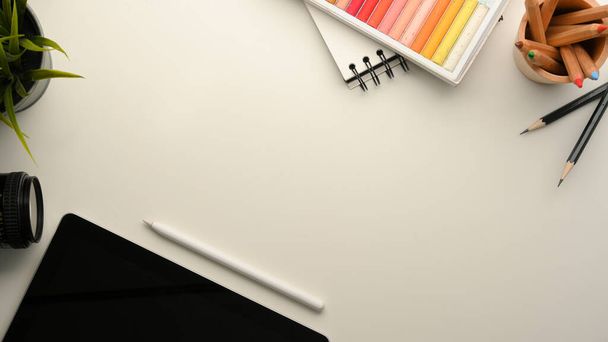 Espacio de trabajo creativo con tableta digital, tiza de color, papelería y espacio de copia sobre fondo blanco - Foto, Imagen