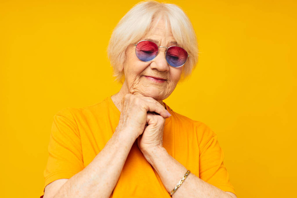 smiling elderly woman in a yellow t-shirt posing yellow background - Photo, image