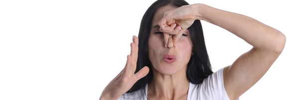 Irritiertes Porträt einer jungen Frau, die Nase vor üblem Geruch verdeckt - Foto, Bild