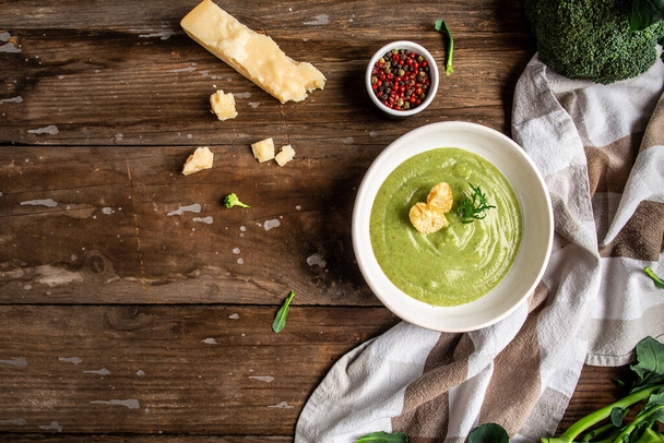 bowl of broccoli cream soup with parmesan cheese and crunchy croutons on wooden table, top view. - Fotoğraf, Görsel