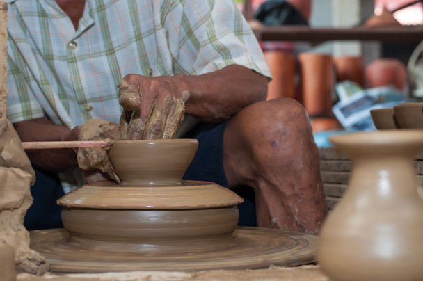 A man shapes pottery as it turns on a wheel - Photo, Image
