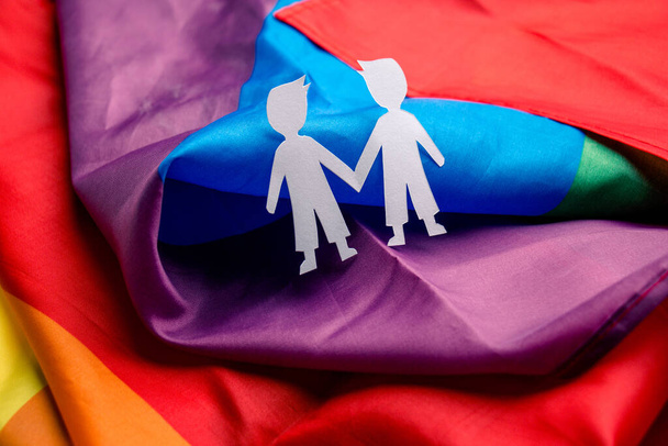 Ο εφημεριδοπώλης κρατάει το χέρι του στην πολύχρωμη σημαία της παρέλασης των ΛΟΑΤΚΙ. Σχέση φιλίας και ανθρώπων, Σεξουαλικός προσανατολισμός έννοια - Φωτογραφία, εικόνα