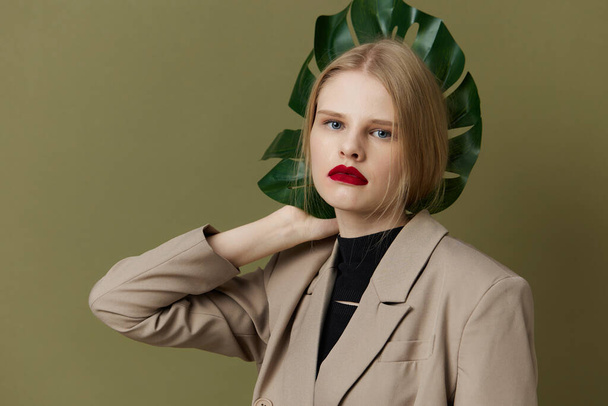 blondi nainen vihreä palmunlehti takki kirkas meikki vihreä tausta - Valokuva, kuva