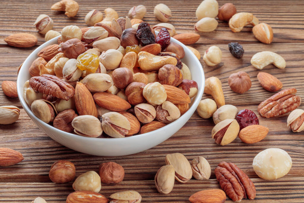 View of mixed nuts on wooden background. Walnut, pistachios, almonds, hazelnuts and cashews. Soft focus. - Φωτογραφία, εικόνα