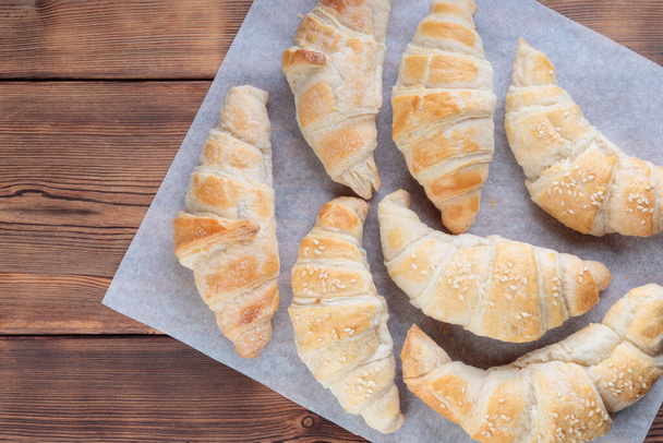 Homemade croissants on a baking paper on wooden background. - Foto, imagen