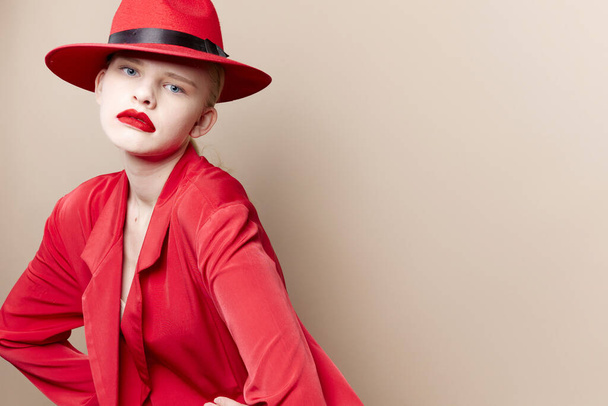 lumoava nainen punainen takki ja hattu punainen huulet muoti beige tausta - Valokuva, kuva