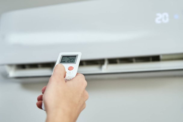 Hand adjusting temperature on air conditioner - Zdjęcie, obraz