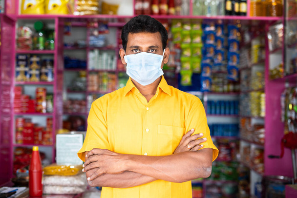 Kirana or groceries Marchant with medical face mak and crossed arms confidently looking at camera - concept of new normal, small and local businesses with coronavirus covid-19 safety measures. - Photo, Image